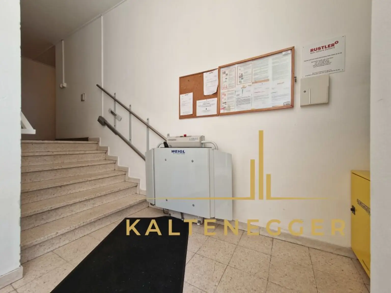 Stiegenhauseingang mit Treppenlift, Postkasterl und Postboxen