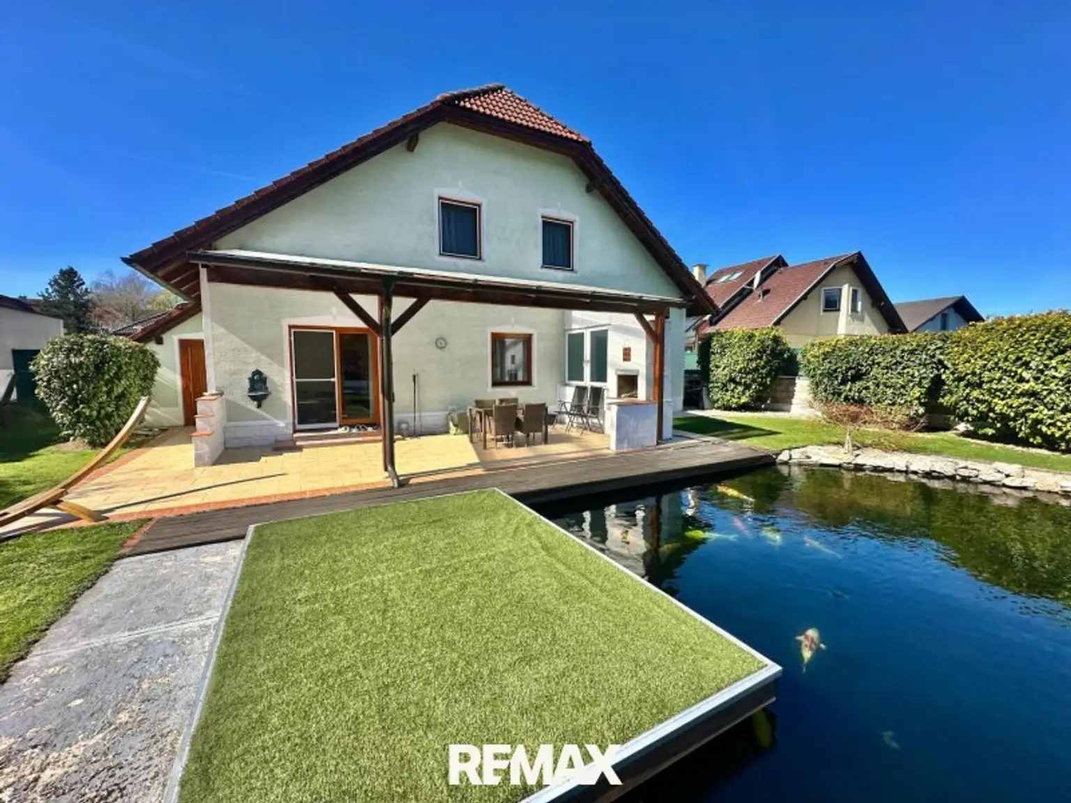Teich mit Terrasse und Hausansicht
