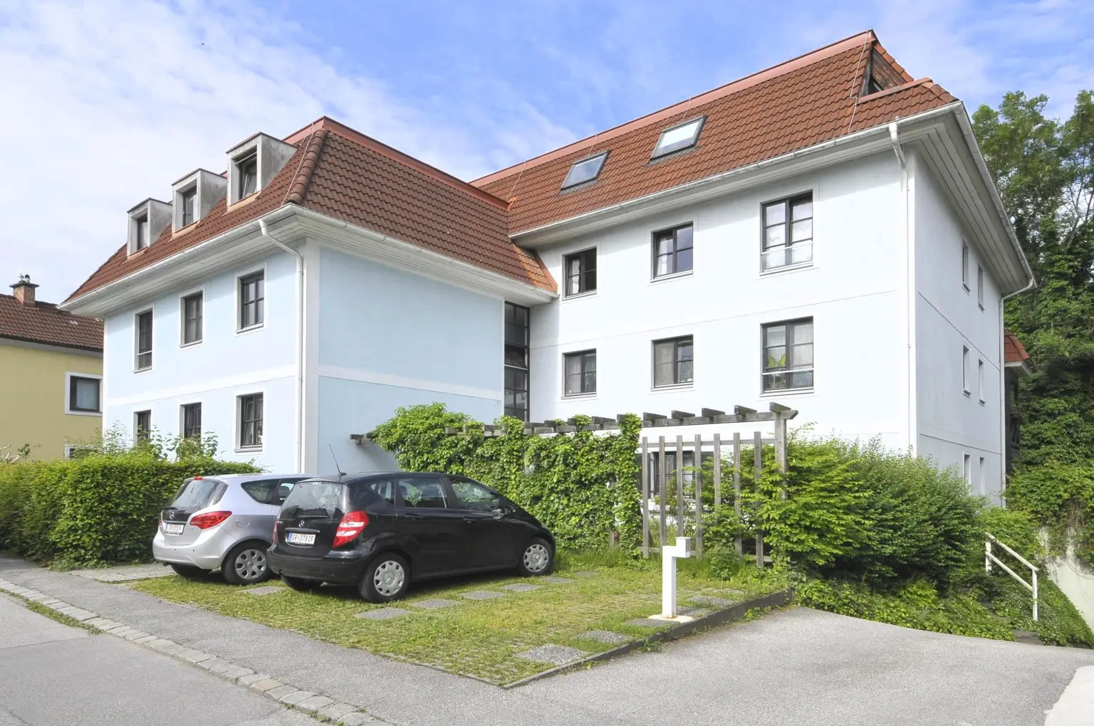 Ostansicht mit TG-Einfahrt und Parkplätze