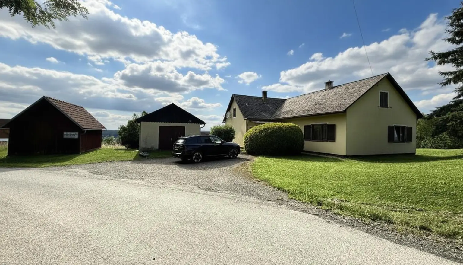 Zufahrt mit Garage und Holzhütte