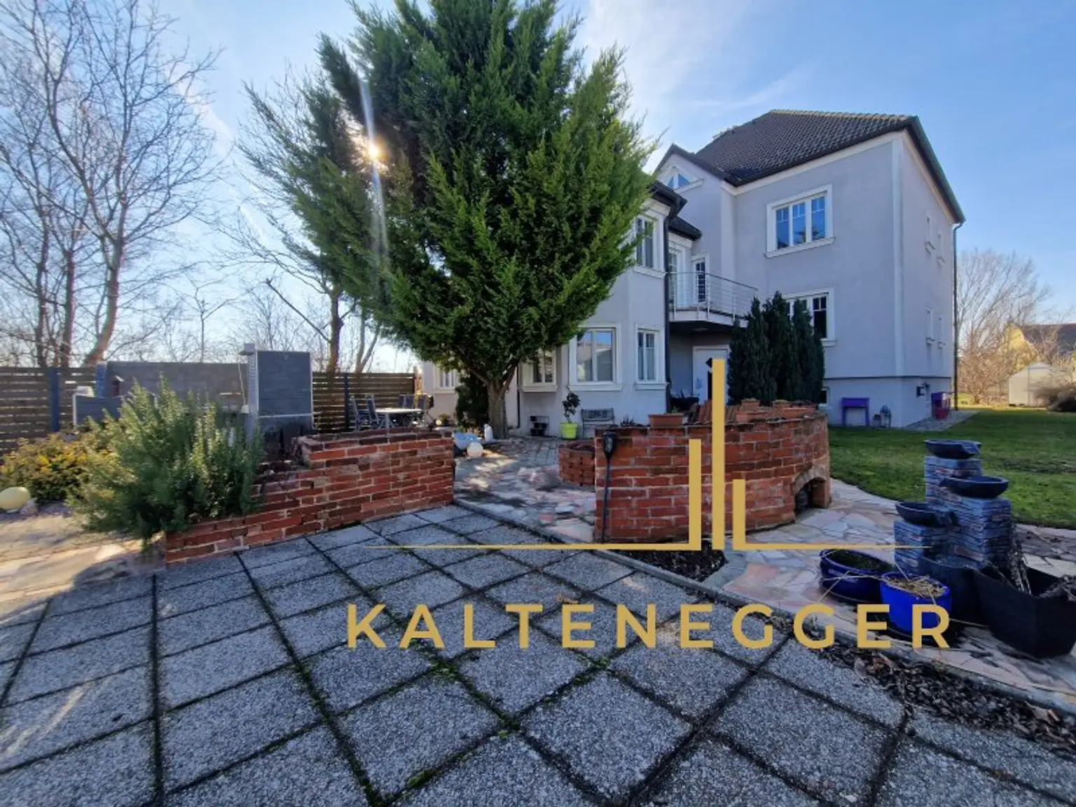 Haus Außenansicht mit gemauerter Sitzecke, Feuerstelle und Outdoorküche