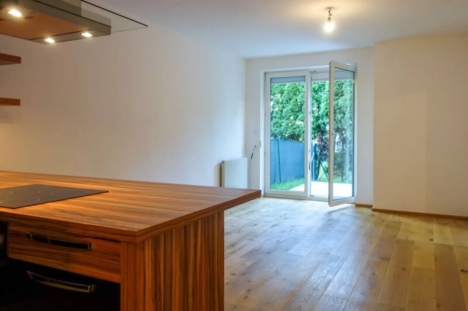 Wohnzimmer mit offener Küche und Ausgang auf Terrasse und in den Garten