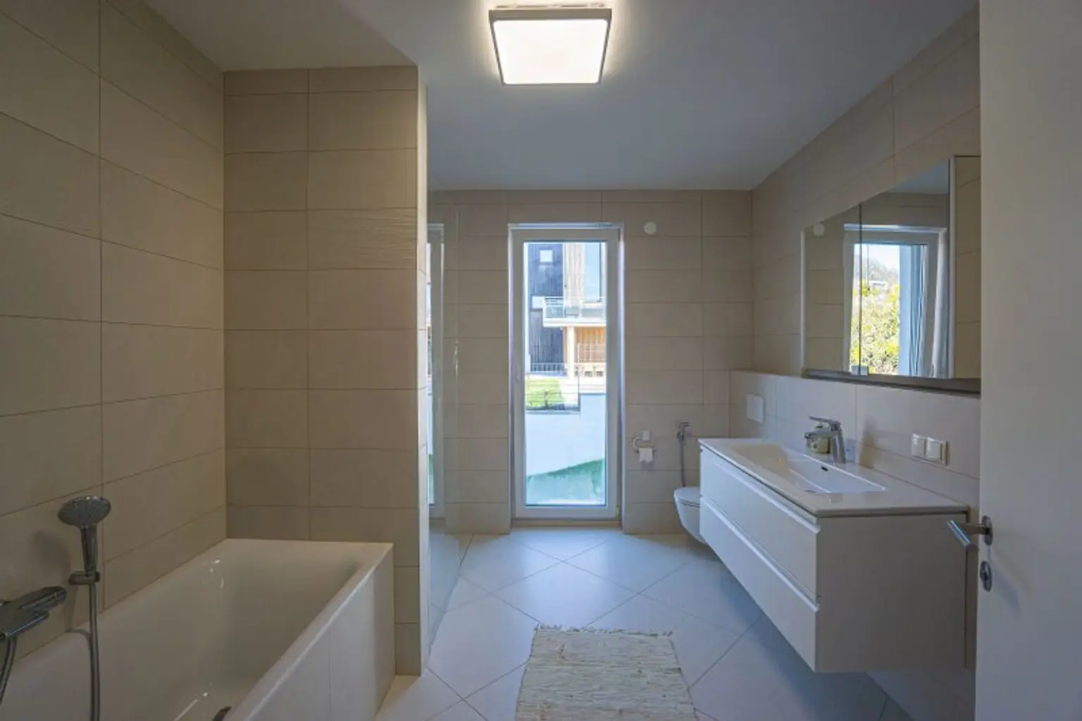 Badezimmer mit Wanne, bodengleicher Dusche, Waschtisch, Spiegelschrank und WC