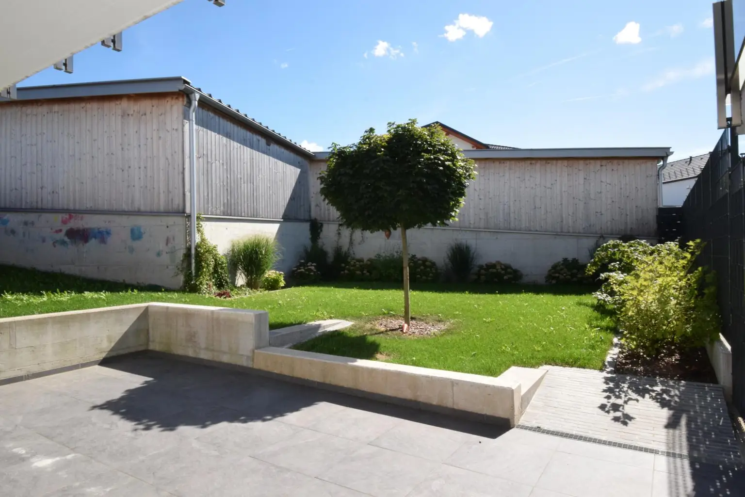 sonnige Terrasse mit Garten